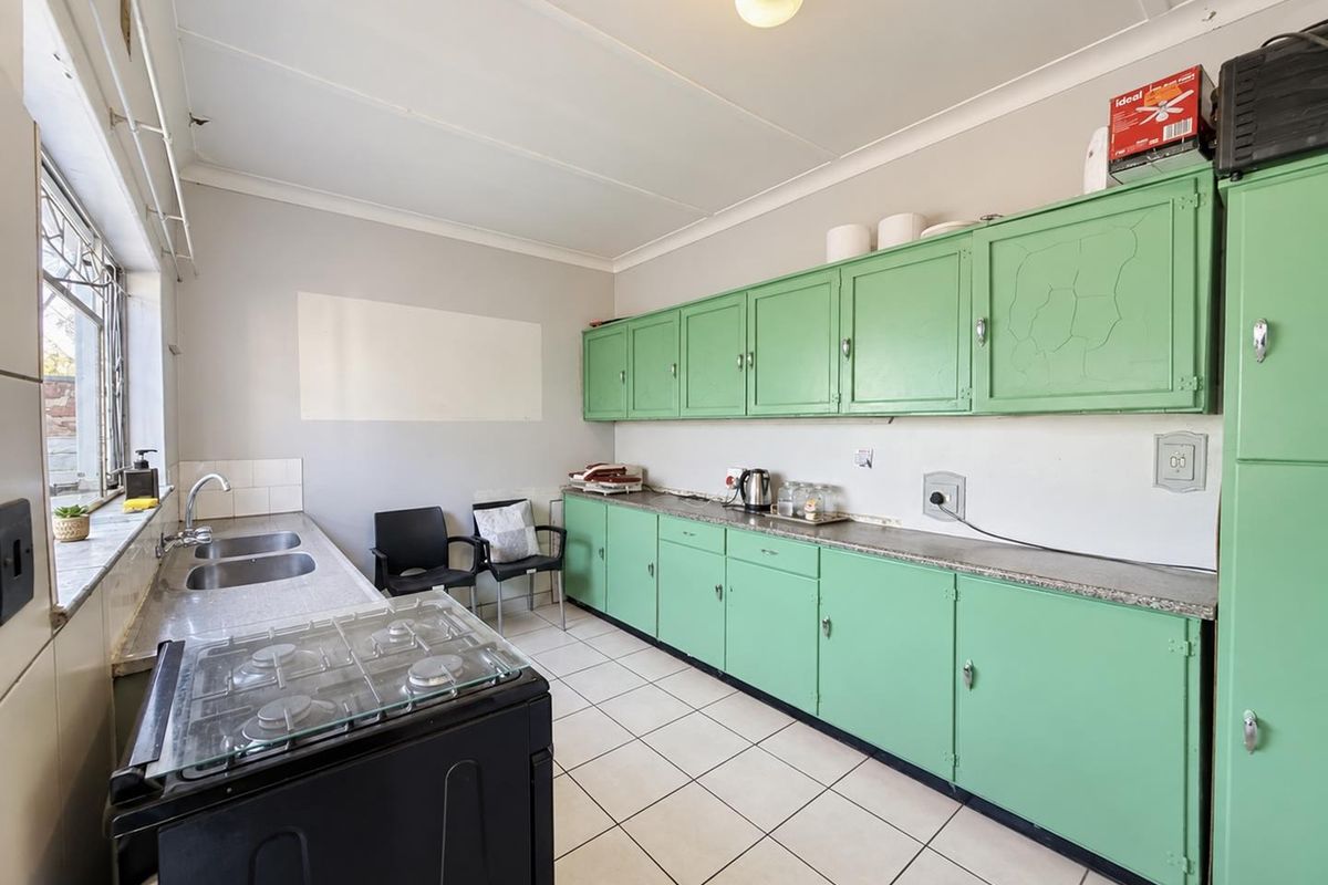 A functional kitchen featuring vintage green cabinetry, tiled flooring, a double sink, and a gas hob with ample counter space.