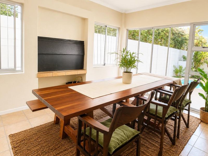 Bright dining room featuring tiled flooring, a built-in fireplace, and large sliding glass doors providing direct access to the outdoor pool area.