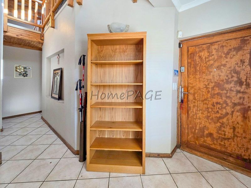 Entrance foyer featuring tiled flooring, a wooden staircase, and a solid wooden front door with a recessed wall niche.