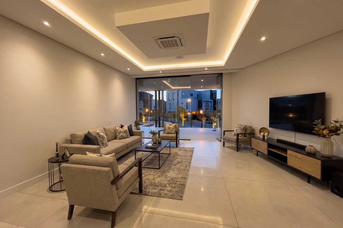 Modern living room featuring large format floor tiles, recessed ceiling with cove lighting, ducted air conditioning, and seamless access to the outdoor patio area.