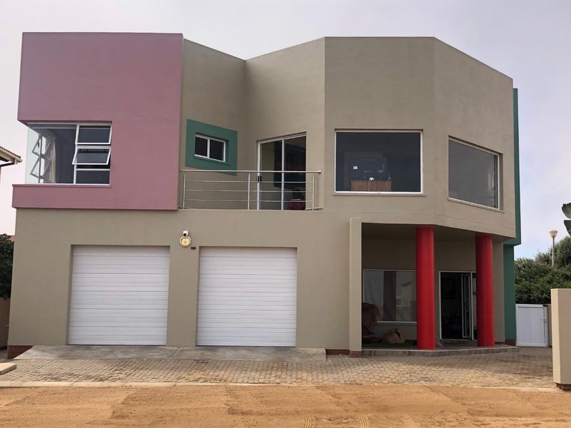 A two-story residential property featuring a double garage, balcony with stainless steel railing, and distinctive architectural design with red support columns.