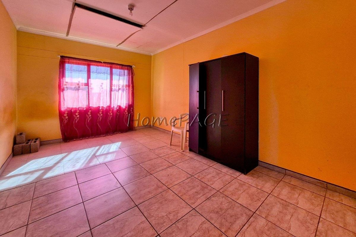 A bedroom featuring tiled flooring, yellow painted walls, and a window with natural light.