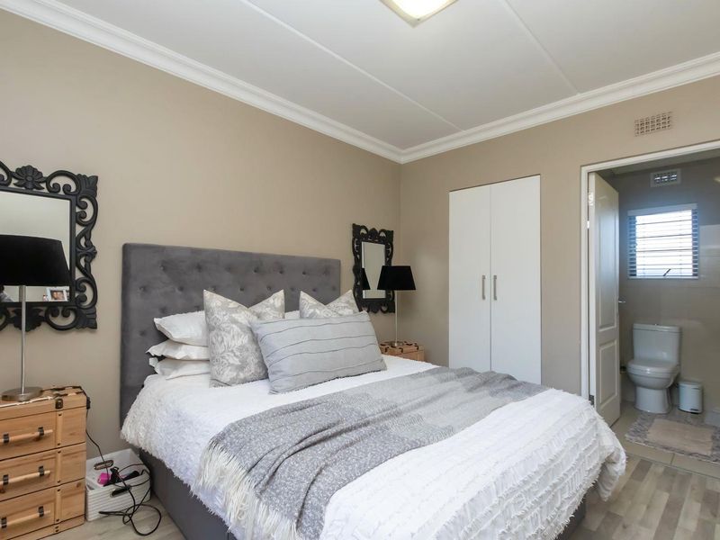 A well-maintained bedroom featuring crown molding, laminate flooring, and a built-in wardrobe, with direct access to an en-suite bathroom.