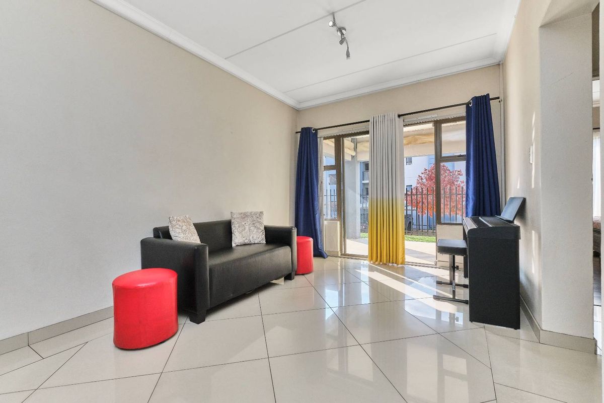A bright living room featuring large glass sliding doors that open to an outdoor area, complemented by polished floor tiles and neutral wall finishes.