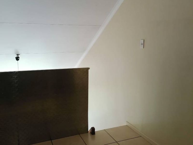 An empty hallway or landing area featuring tiled flooring and a metal balustrade, showing signs of wear on the ceiling finishes.