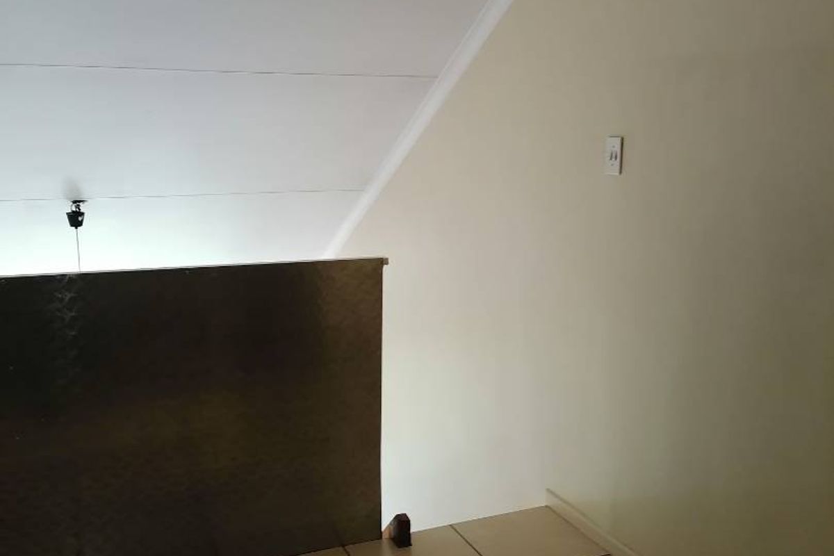 An empty hallway or landing area featuring tiled flooring and a metal balustrade, showing signs of wear on the ceiling finishes.