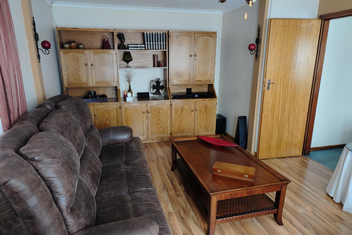 A living room featuring built-in oak cabinetry, laminate wood flooring, and a solid timber door leading to an adjacent space.