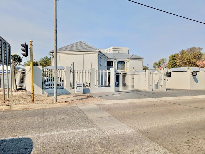 Front exterior view of a commercial office property featuring secure perimeter fencing, electric security wires, and a paved driveway with a gated entrance.