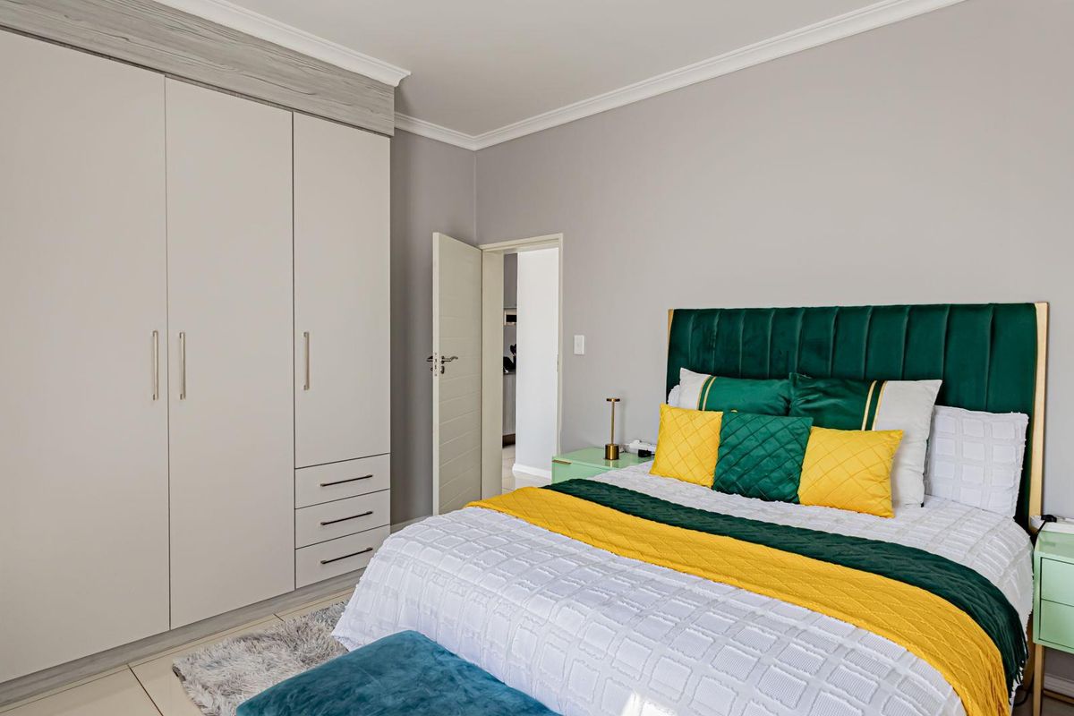 A well-maintained bedroom featuring neutral walls, crown molding, tiled flooring, and ample built-in cupboard storage.