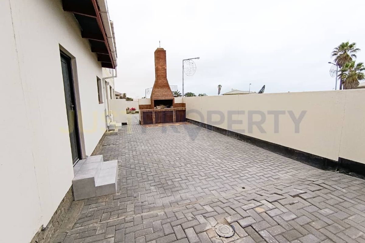 A paved rear courtyard featuring a built-in brick braai fireplace and high boundary walls, providing a private outdoor entertainment space.