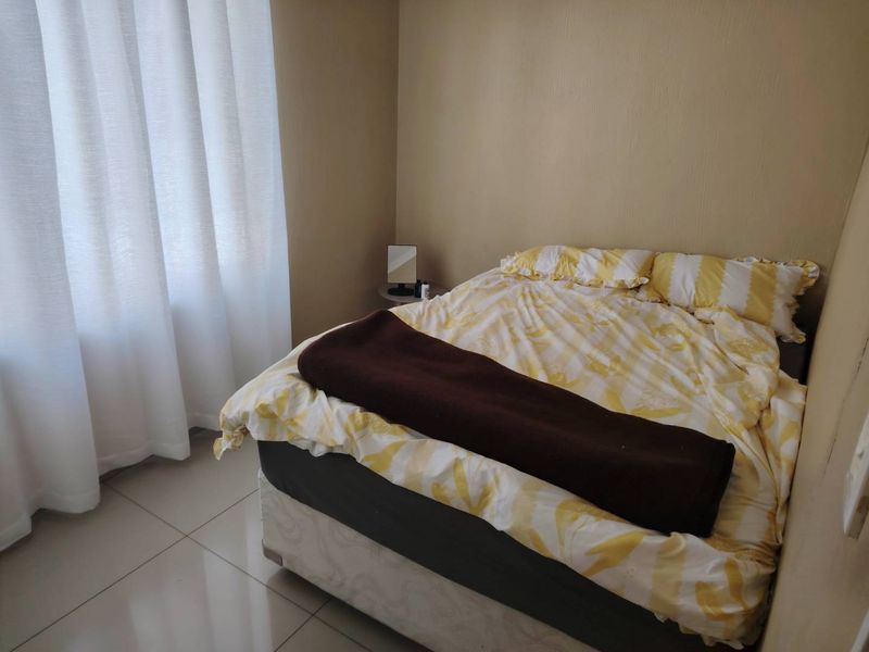 A functional bedroom featuring neutral wall tones and tiled flooring, providing a simple and clean space for rest.