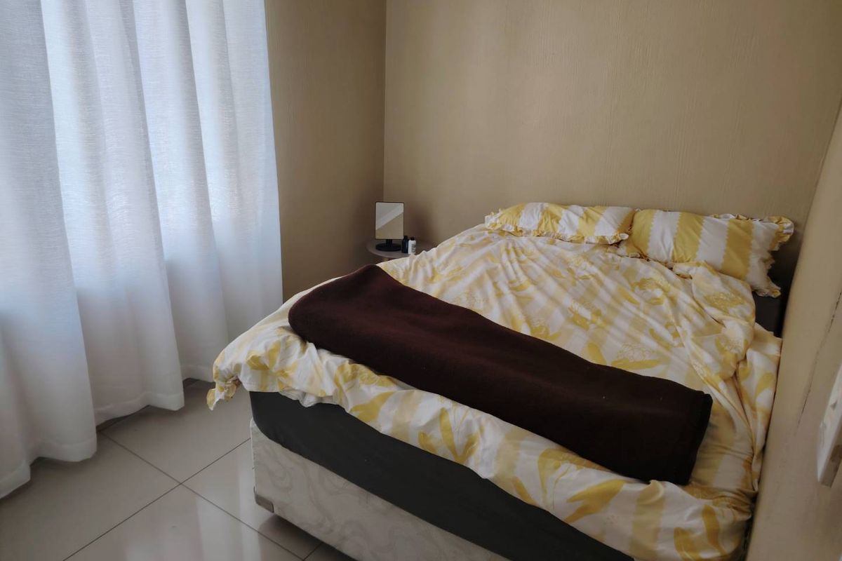A functional bedroom featuring neutral wall tones and tiled flooring, providing a simple and clean space for rest.