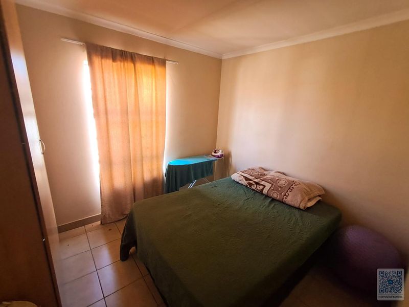 A standard bedroom featuring tiled flooring and a built-in cupboard, offering a functional space with natural light.