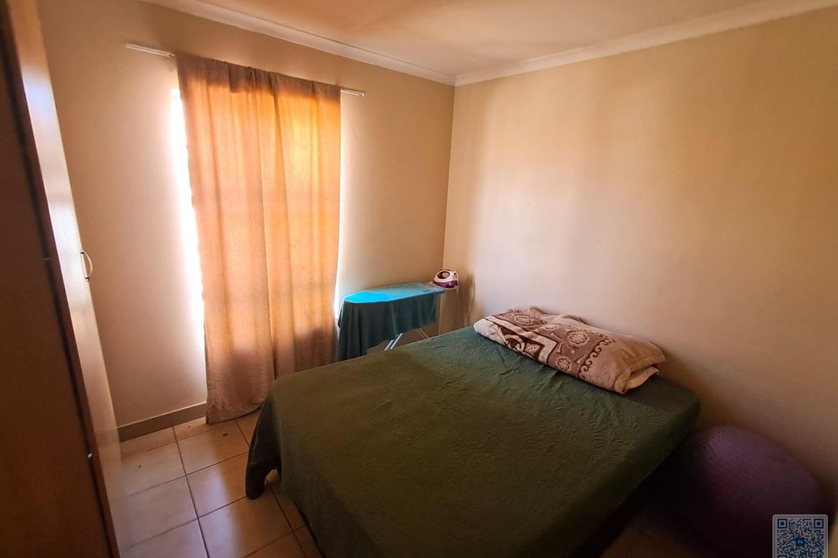 A standard bedroom featuring tiled flooring and a built-in cupboard, offering a functional space with natural light.
