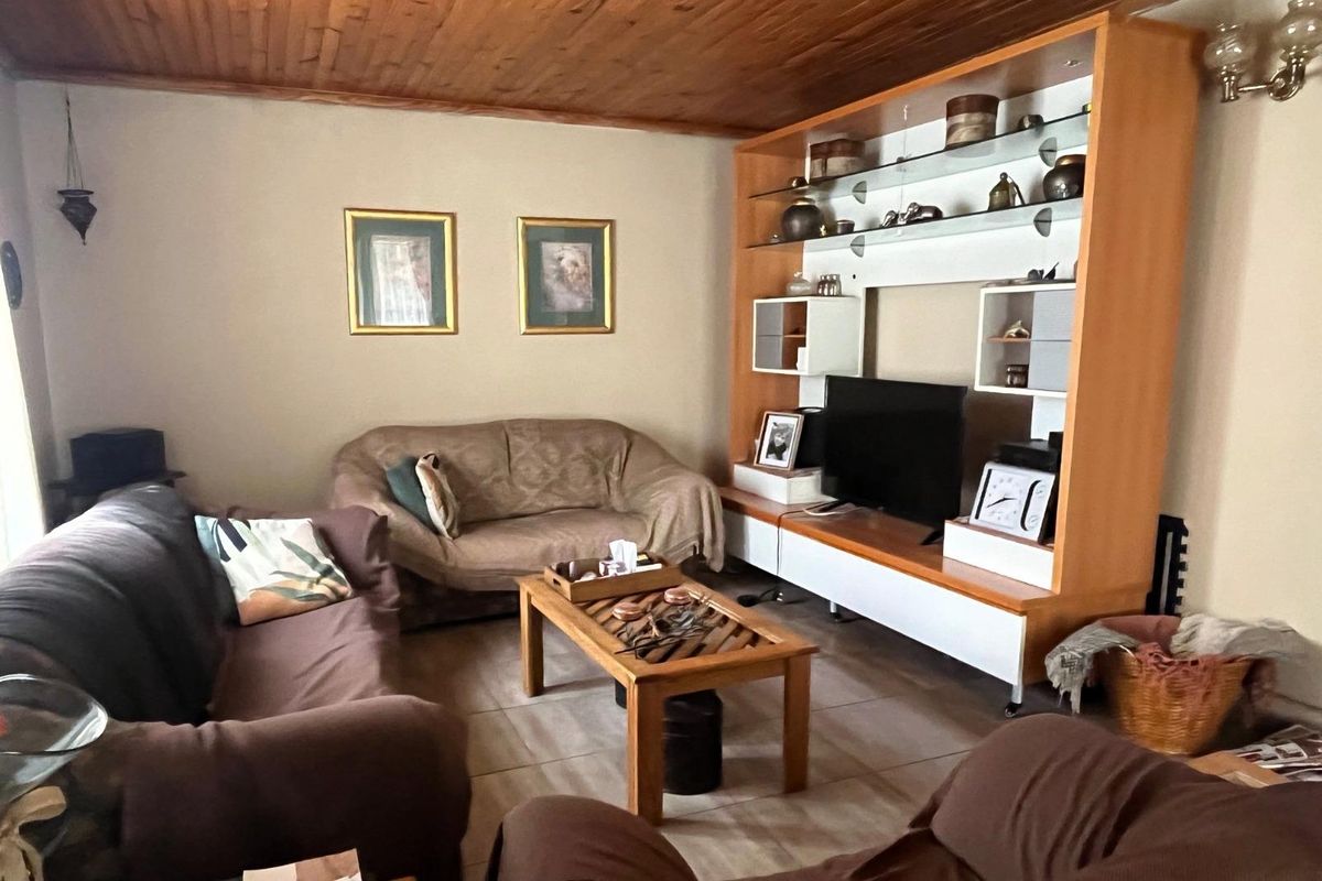 A living room featuring a timber-clad ceiling and a large built-in wooden shelving unit with integrated display space.