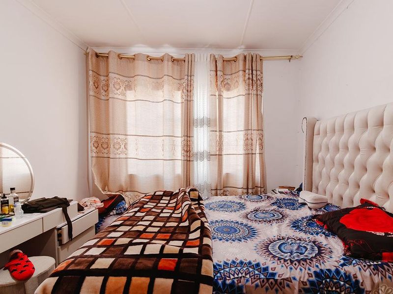 A bedroom featuring neutral walls and a window dressed with patterned curtains.