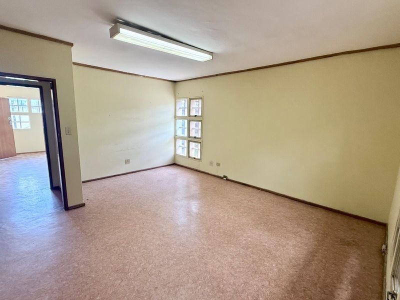 An empty, functional office space featuring neutral walls, vinyl flooring, and a fluorescent light fixture, offering a blank canvas for professional use.