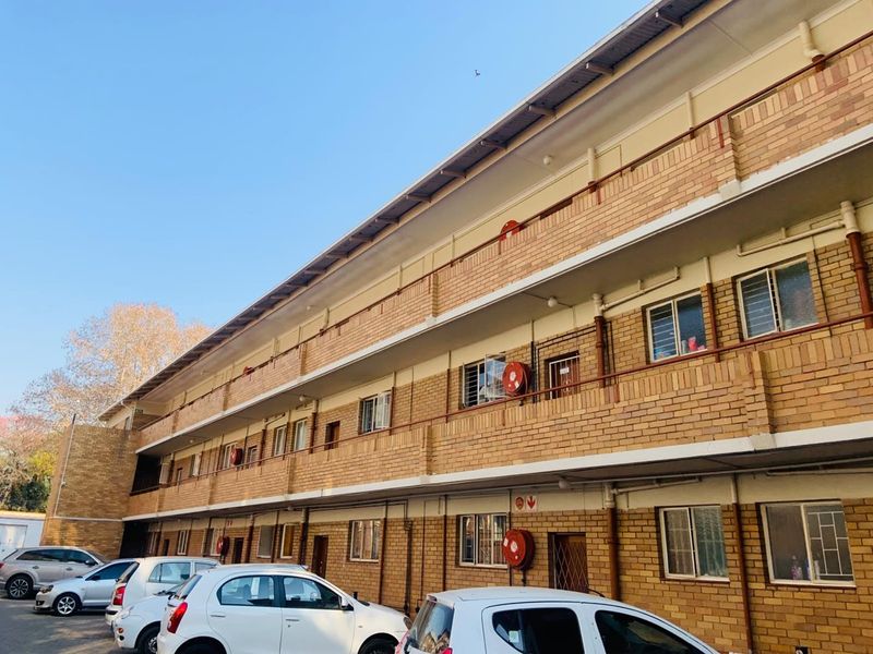 Exterior view of a multi-story apartment building featuring face brick construction, balcony walkways, and secure window fittings.