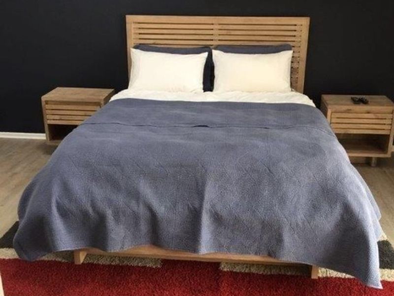 A bedroom featuring a dark accent wall with mounted floating shelves and wood-toned flooring.