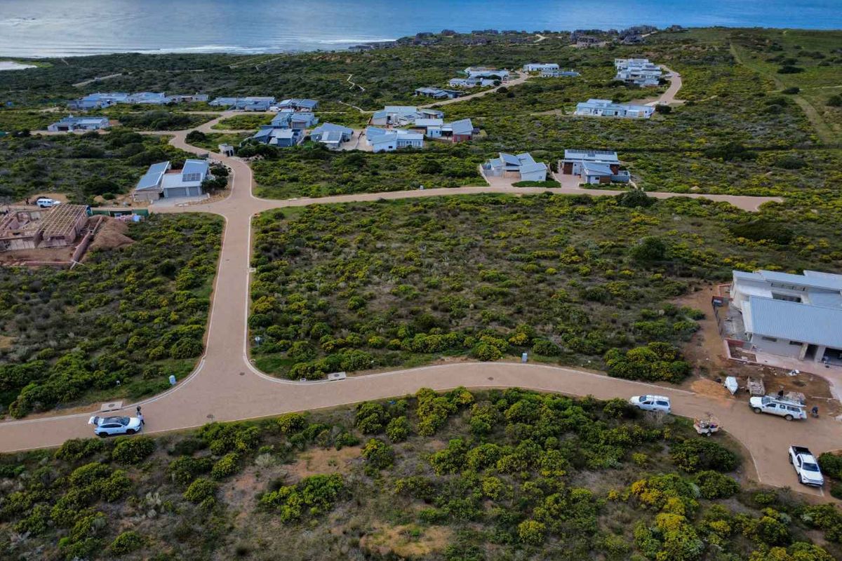 Aerial view of a residential coastal estate featuring paved roads and surrounding natural vegetation with ocean views.