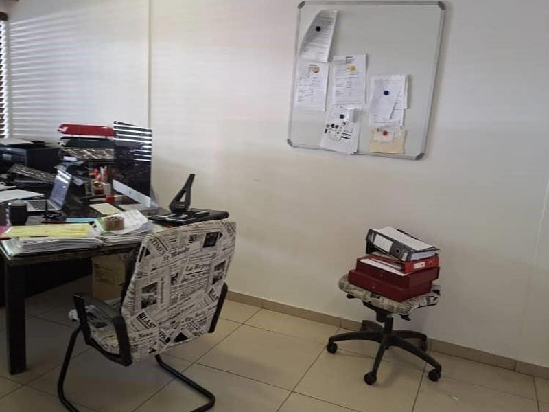 A functional office space featuring ceramic floor tiles, recessed ceiling lighting, and window blinds, providing a practical work environment.