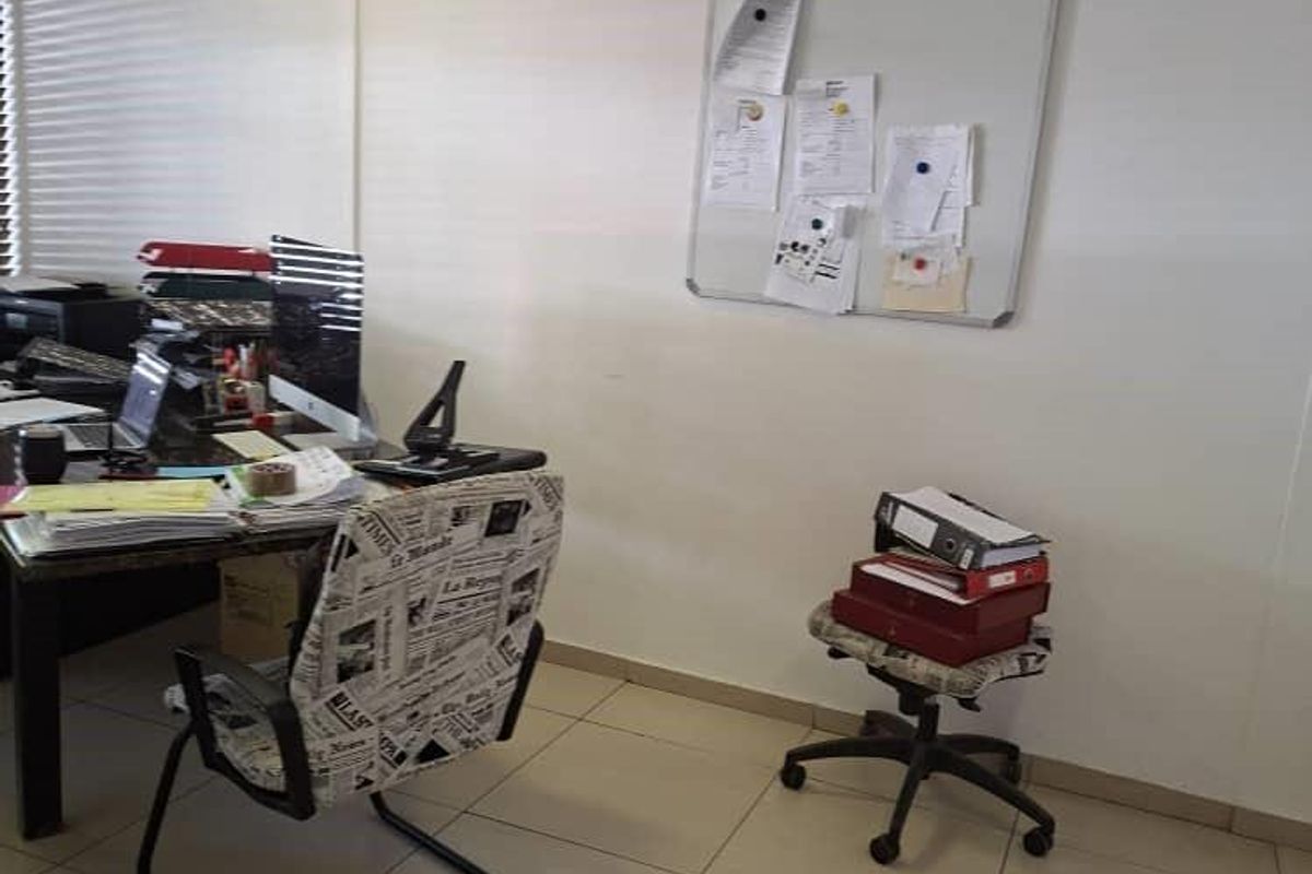 A functional office space featuring ceramic floor tiles, recessed ceiling lighting, and window blinds, providing a practical work environment.