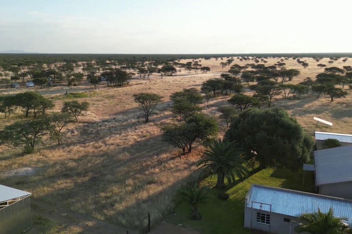 Aerial view of the farm property showing the main buildings with metal roofing, solar panels, and the surrounding expansive landscape.