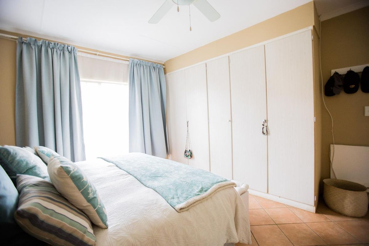 A bedroom featuring built-in cupboards, a ceiling fan, and tiled flooring, offering a functional and comfortable living space.