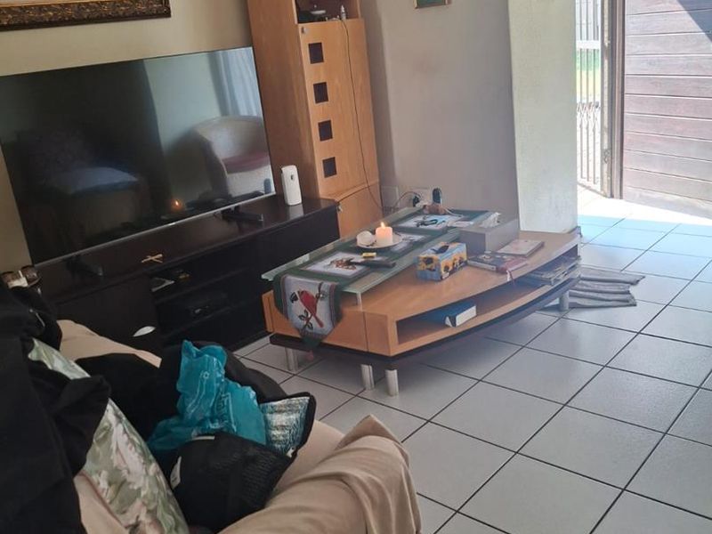 A living room area featuring tiled flooring and direct access to an outdoor space through a sliding door.