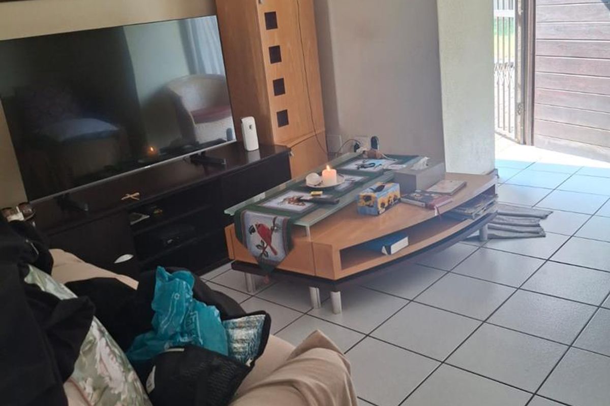 A living room area featuring tiled flooring and direct access to an outdoor space through a sliding door.