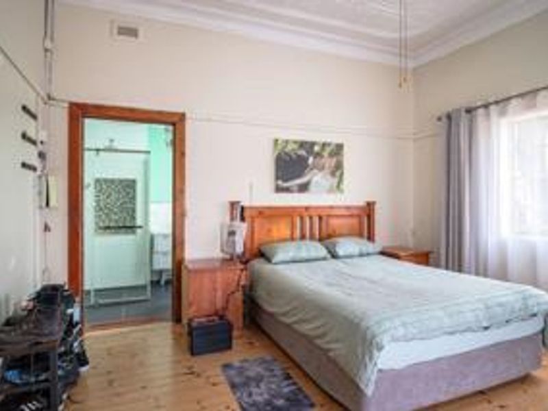 A bedroom featuring timber flooring, ornate ceiling detailing, and direct access to an en-suite bathroom.