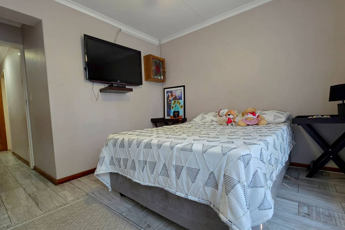A functional bedroom featuring tiled flooring, coved ceilings, and a wall-mounted television setup.
