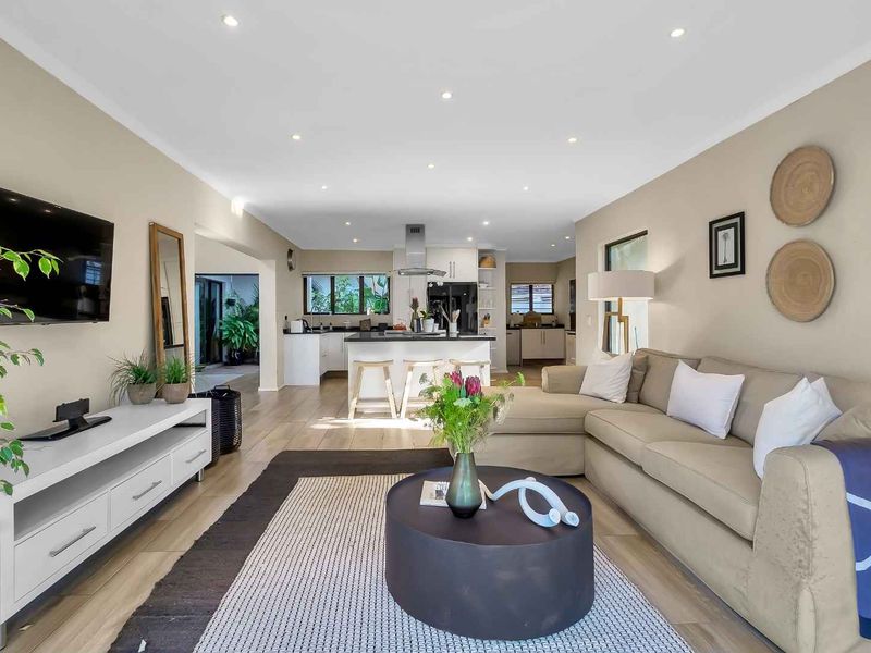 Spacious open-plan living area featuring a modern kitchen with a central island, recessed lighting, and neutral finishes throughout.