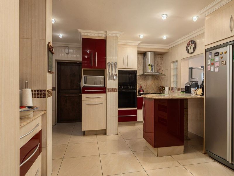 A well-appointed kitchen featuring high-gloss cabinetry, granite countertops, built-in appliances, and tiled flooring with recessed lighting.