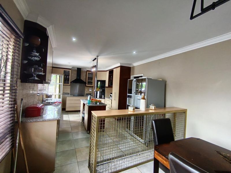 A well-appointed kitchen featuring granite countertops, ample built-in cabinetry, a central island, and tiled flooring, offering a functional and organized cooking space.
