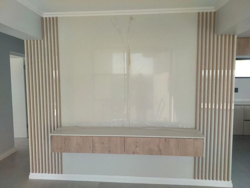 A modern living room feature wall with vertical timber slats and a floating storage unit, presenting a clean, contemporary aesthetic.