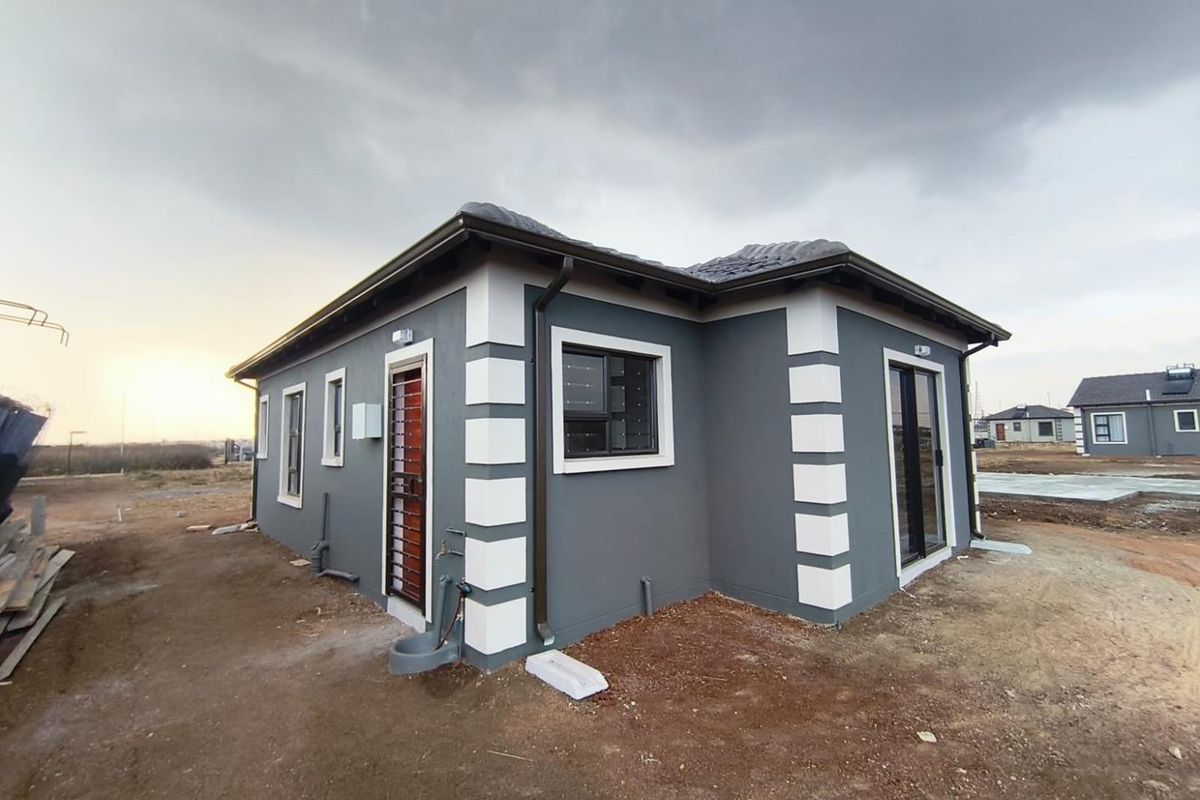 Rear view of a modern single-story house featuring a grey plastered facade with white corner detailing, sliding doors, and security gates.