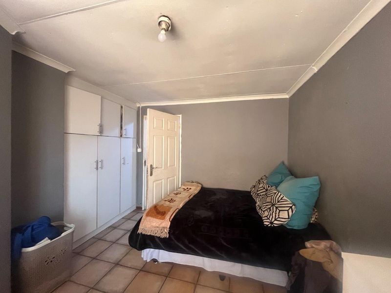 A bedroom featuring built-in cupboards, tiled flooring, and a coved ceiling, requiring some maintenance to the ceiling and flooring finishes.