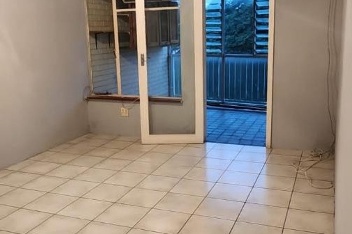 An empty living room featuring tiled flooring, a ceiling fan, and direct access to an outdoor balcony area.