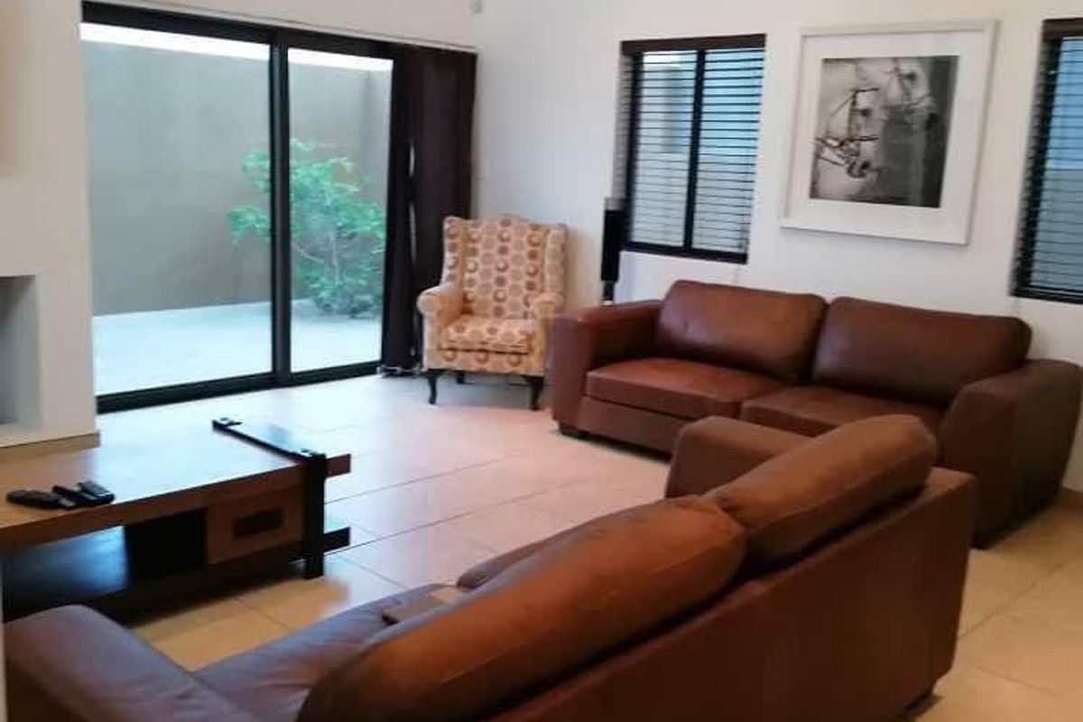 Spacious living room featuring tiled flooring, large sliding glass doors leading to the patio, and a classic chandelier.