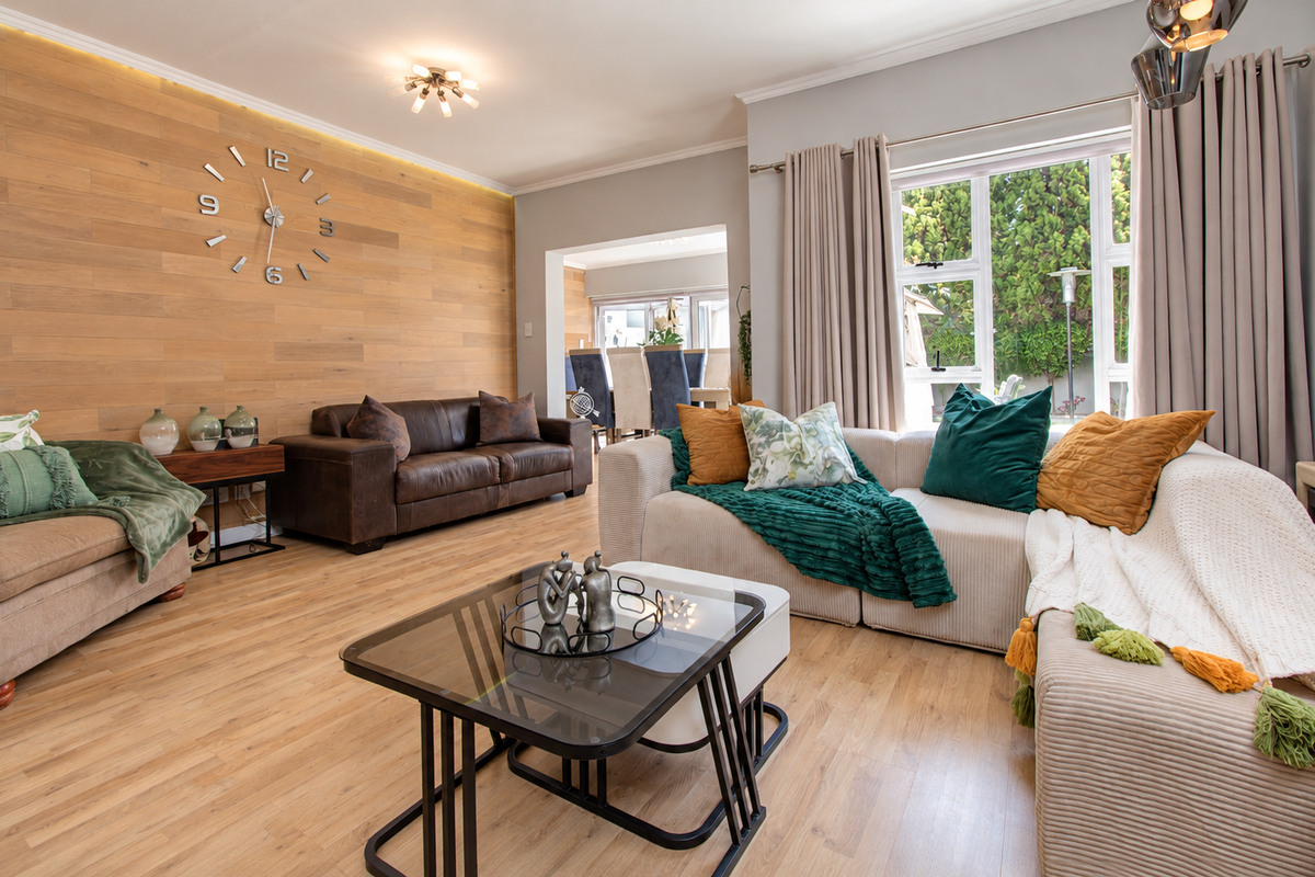 A well-appointed living room featuring a timber-clad feature wall, warm laminate flooring, and large windows that provide ample natural light.