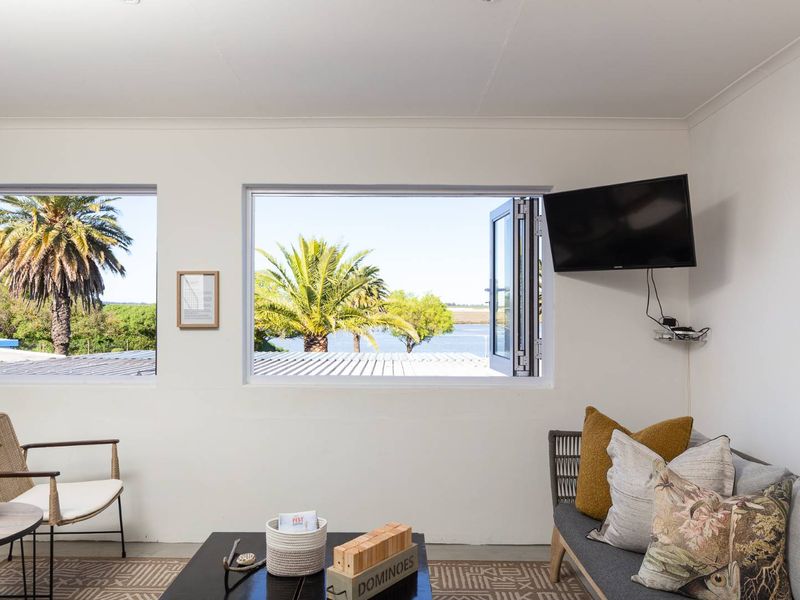 A bright living area featuring large windows with scenic water and palm tree views, providing natural light and a tranquil atmosphere.