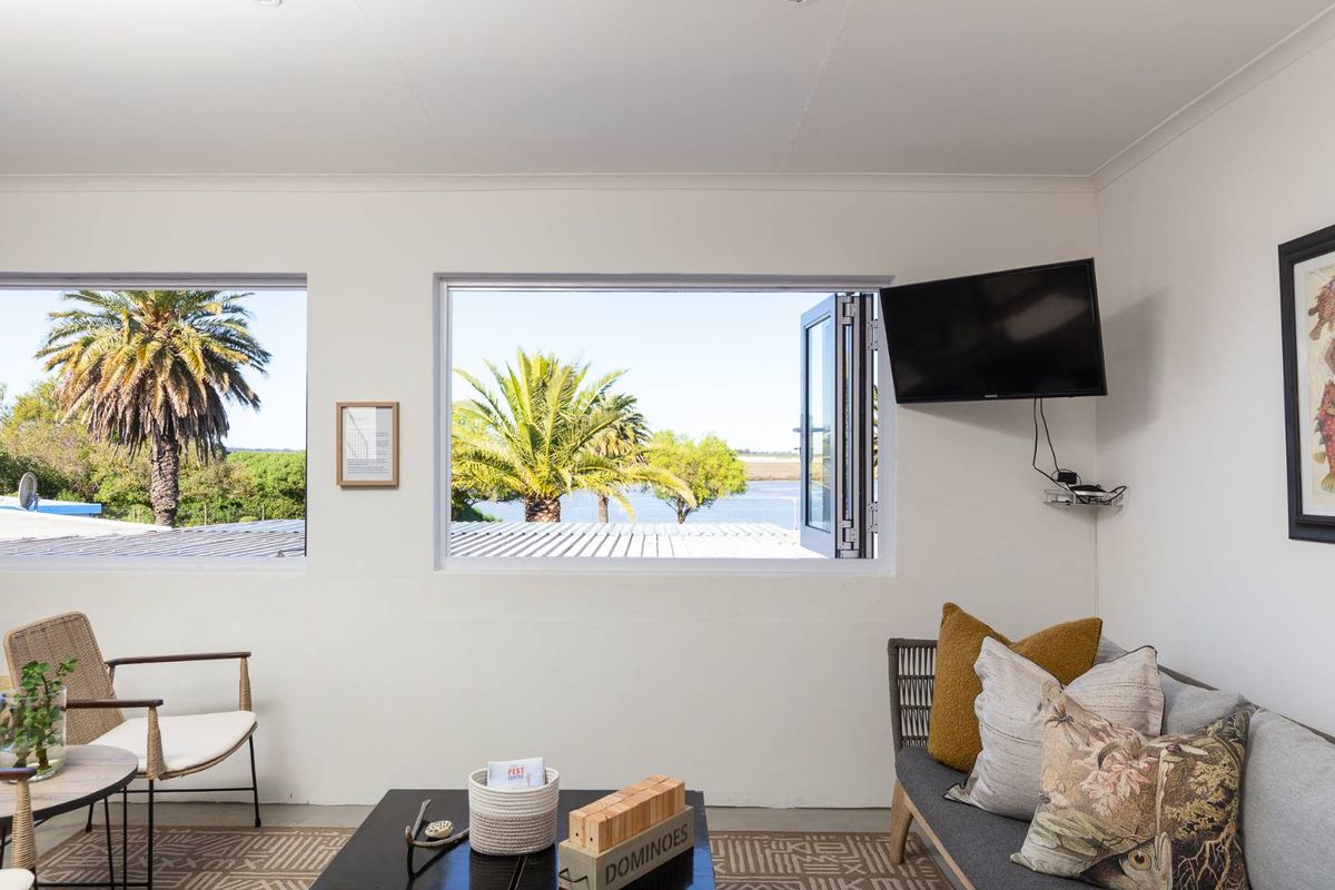 A bright living area featuring large windows with scenic water and palm tree views, providing natural light and a tranquil atmosphere.