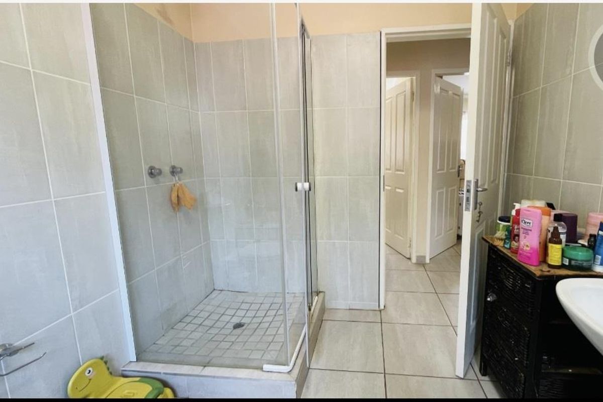 A functional bathroom featuring a glass-enclosed shower stall with tiled walls and flooring, providing a clean and practical layout.