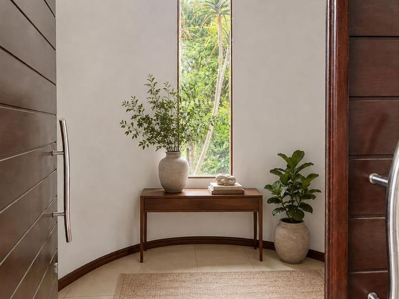 A bright and welcoming entrance foyer featuring a tall vertical window, tiled flooring, and a modern timber door.