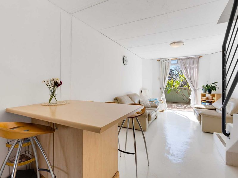 Open-plan living area featuring a breakfast bar, staircase, and direct access to a balcony through sliding glass doors.