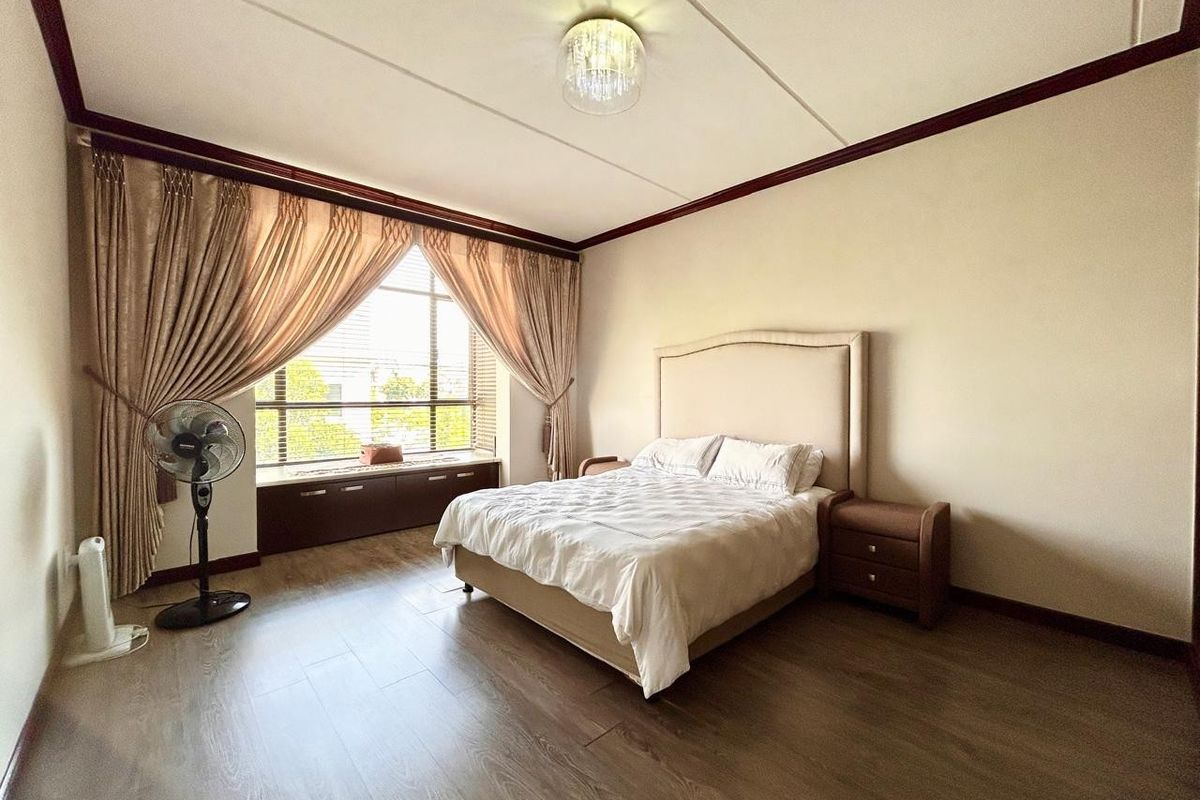 Spacious bedroom featuring laminate flooring, a built-in window seat, and neutral wall finishes, offering a comfortable and well-maintained living space.