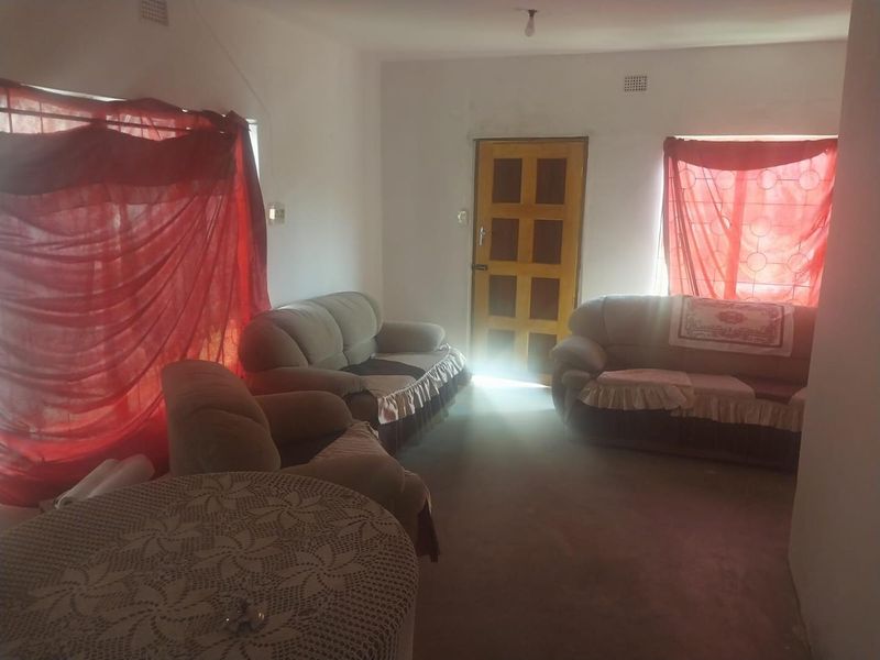 A living room area featuring a timber entrance door and security bars on the windows, requiring cosmetic updates to improve the overall aesthetic.