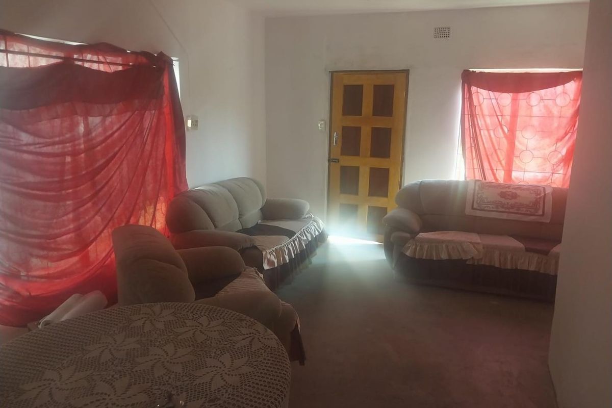 A living room area featuring a timber entrance door and security bars on the windows, requiring cosmetic updates to improve the overall aesthetic.