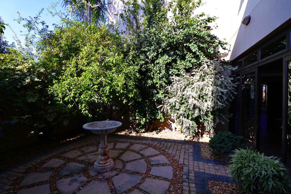 A private rear courtyard featuring a circular stone paved patio, a decorative stone bird bath, and direct access to the home via sliding glass doors.